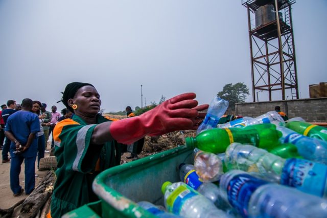 A woman places plastic waste in a bin, Lagos, Nigeria