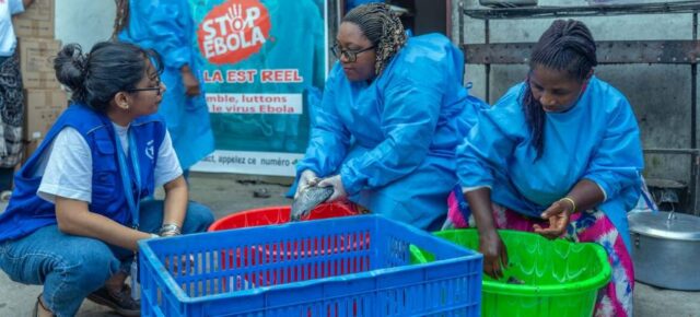 A WFP worker speaks to women preparing food for people affected by Ebola
